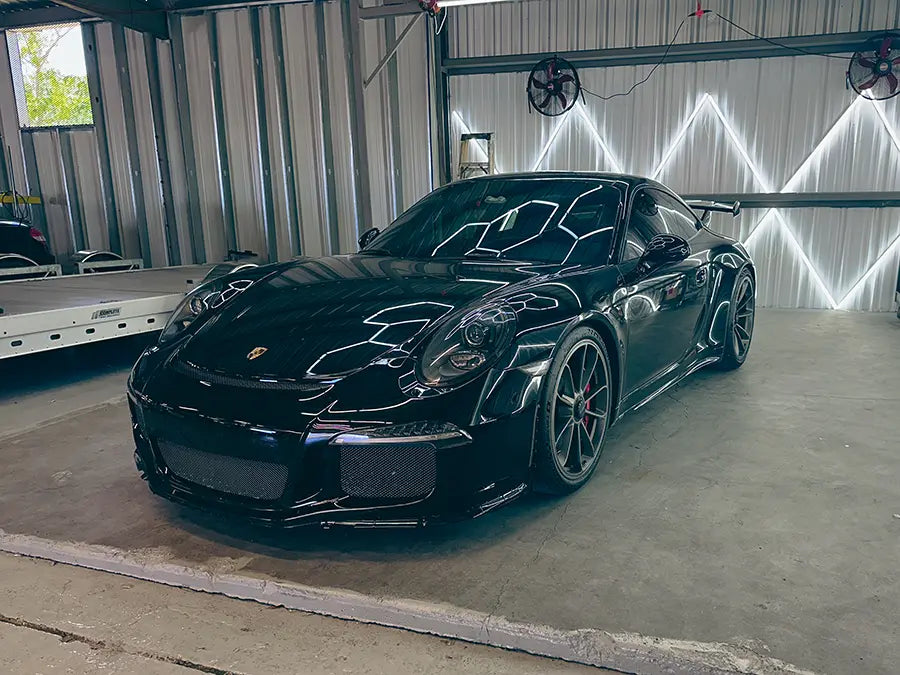 A black Porsche 911 parked in the display corner of the Superior Autohaus garage.