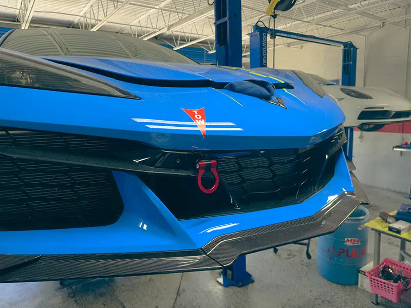 Close-up of the front of a blue Chevrolet Corvette up on a lift in the Superior Autohaus garage.