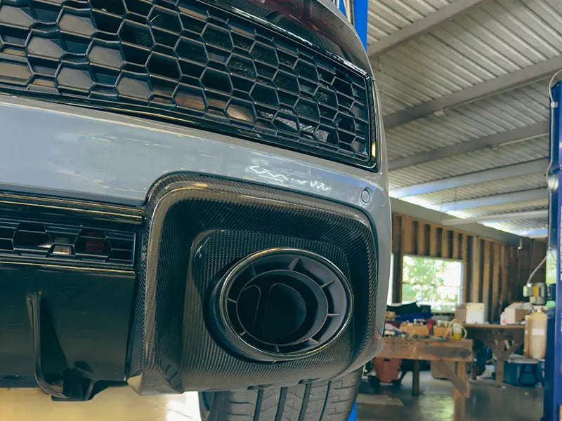 The exhaust tail pipe of a gray Audi R8 on a lift in the Superior Autohaus garage.