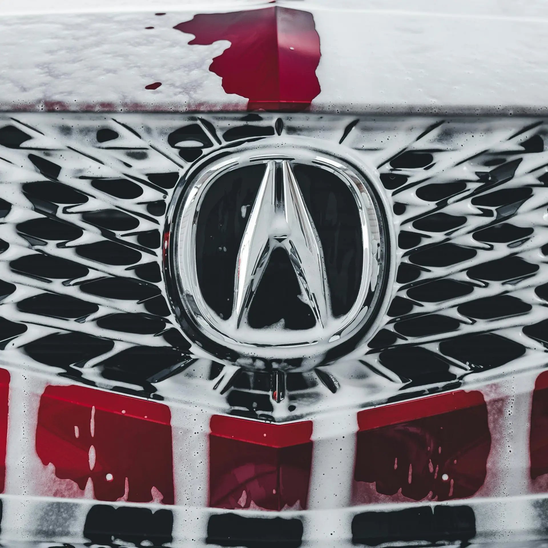 Acura badge on a red car being washed. 