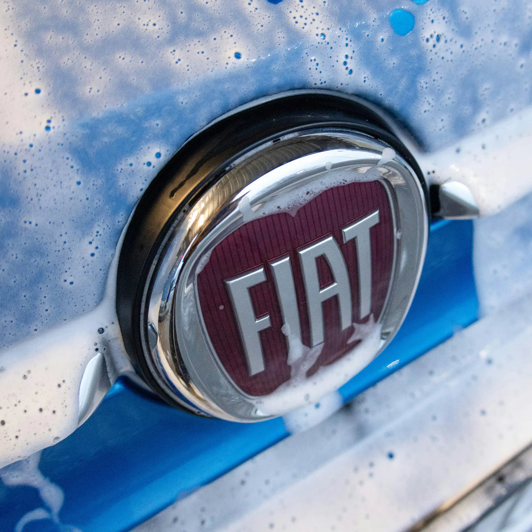 Fiat badge on a blue car being washed. 