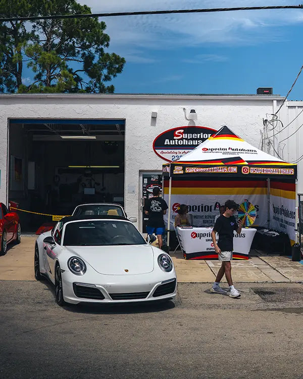 A white Porsche 911 parked near the entrance of the Superior Autohaus garage, attending a local event they are hosting in Bonita Springs, Florida. 
